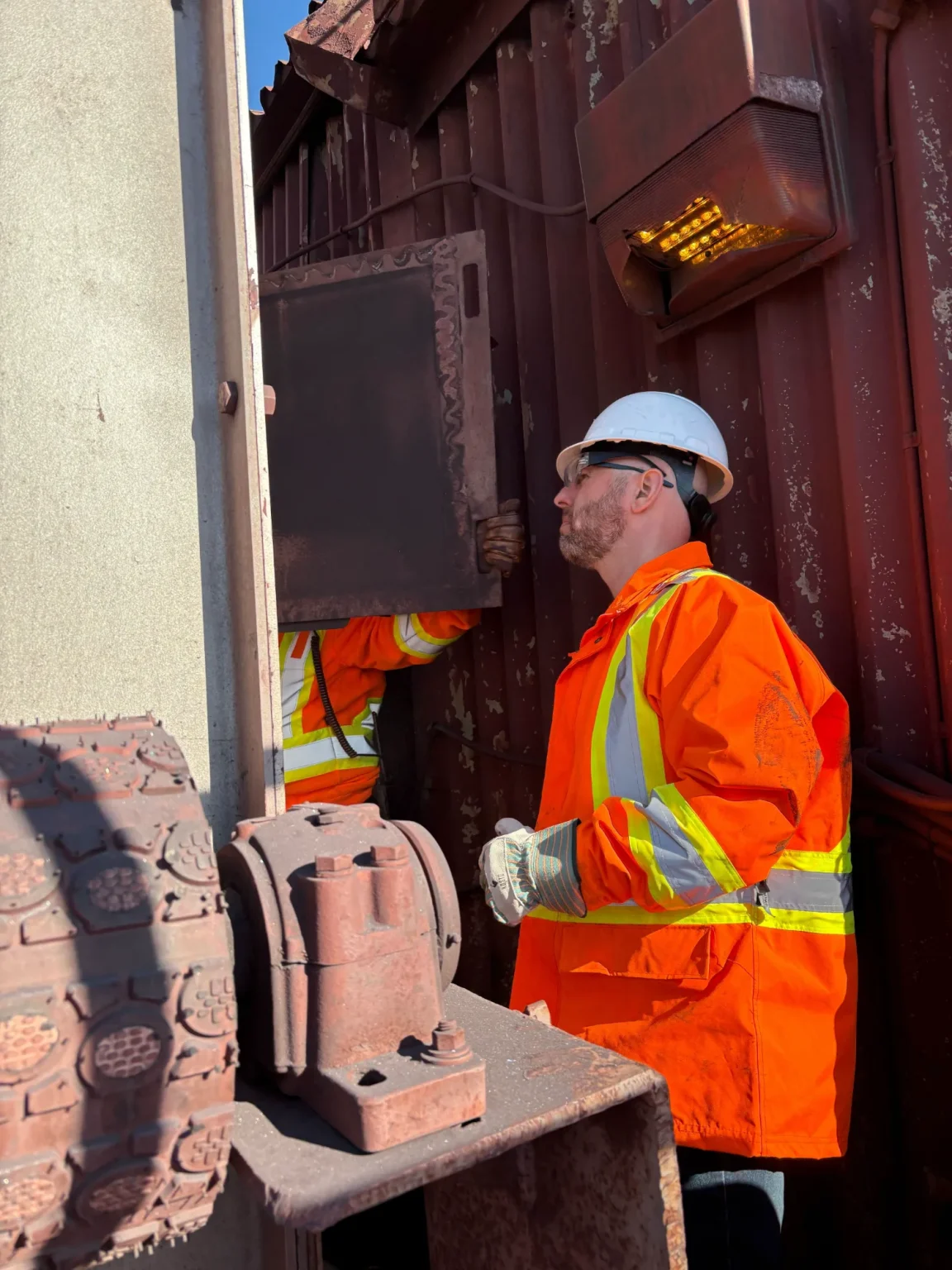 Worker in high-visibility clothing inspecting equipment on site.