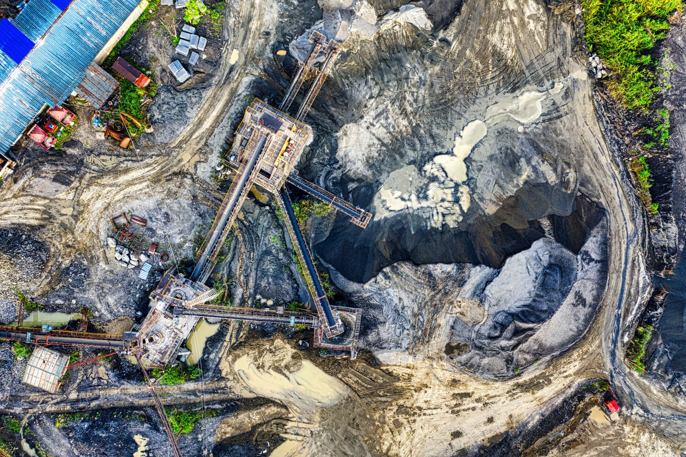 Site minier vu à la verticale : fosses, pistes d'accès et machinerie.